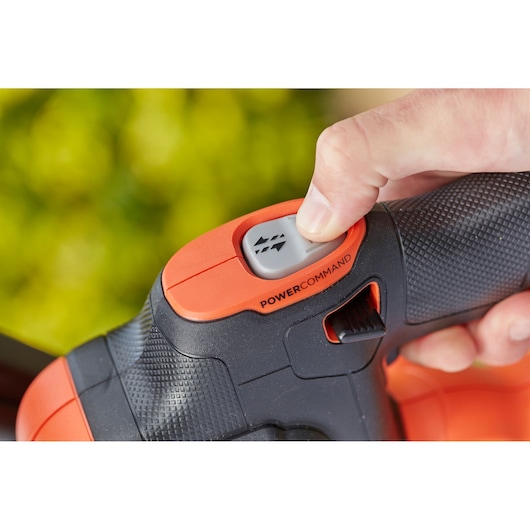 Close-up photo of BLACKDECKER BCHTS3625L1 hedge trimmer handle with PowerCommand button being pressed.