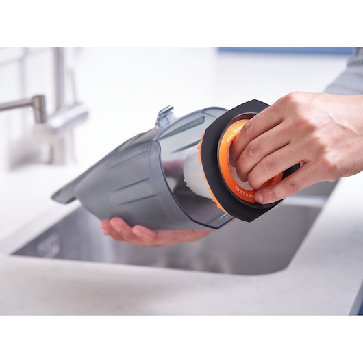 Photo of a person removing the filter from a BLACKDECKER BCHV001B handheld vacuum over a sink.