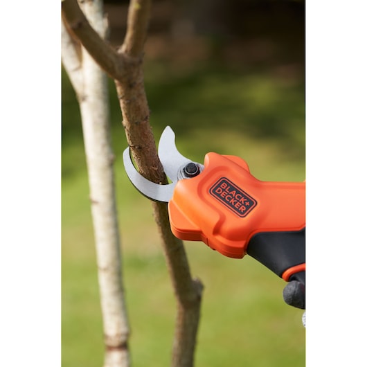 Close up of BLACK+DECKER 18V Power Pruner cutting blades on a branch.