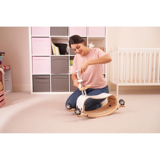 BLACKDECKER BCRTA01 tool being used to assemble a wooden ride-on toy in a nursery setting.
