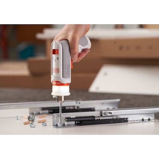 BLACKDECKER BCRTA01 cordless screwdriver in use assembling metal drawer slides and screws.