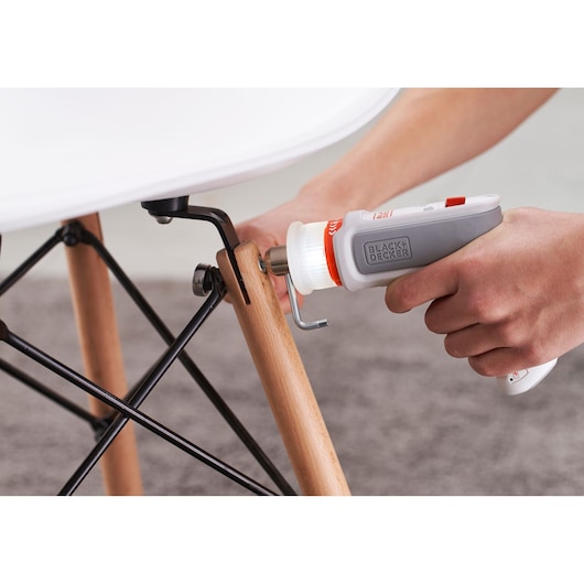 Photo of BLACK+DECKER BCRTA01 screwdriver in hand tightening a bolt on a wooden chair leg.