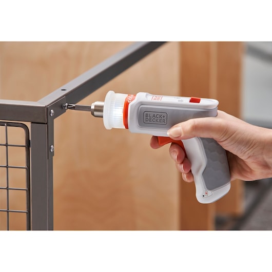 BLACKDECKER BCRTA01 cordless screwdriver in use assembling metal furniture, close-up side angle.