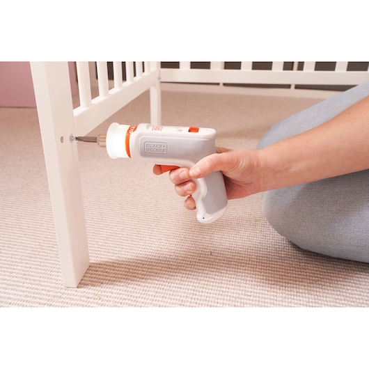 Photo of BLACK+DECKER BCRTA01 cordless screwdriver being used to assemble white furniture on carpet.