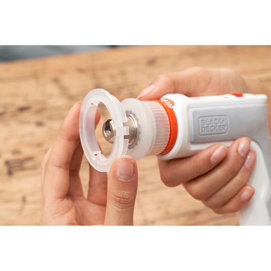 Close-up photo of BLACK+DECKER BCRTA01 rotary tool with clear attachment being installed, person holding tool.