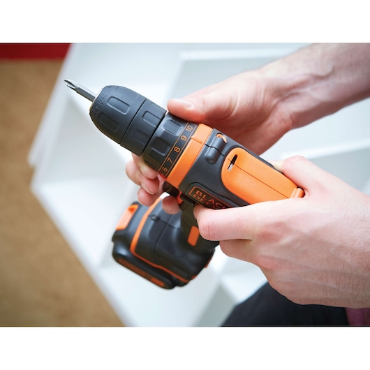 Photo of BLACKDECKER BDCDD12 cordless drill driver held in hands, black and orange design, close-up view.