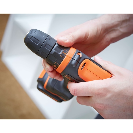 Photo of BLACKDECKER BDCDD12 cordless drill in use, black and orange design, close-up view.