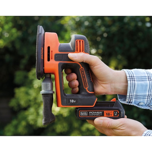 Photo of BLACK+DECKER 18V cordless sander BDCDS18 held in hand, showing side view and battery details.