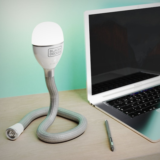 BLACK+DECKER BDCFSL01 flexible desk lamp with braided hose stand next to a laptop and pen on a wooden table.