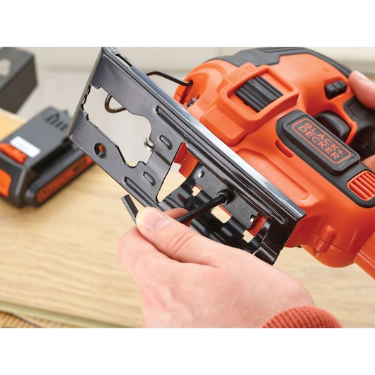 Close-up photo of BLACK+DECKER BDCJS18 jigsaw being adjusted with a hex key, black and orange design visible.
