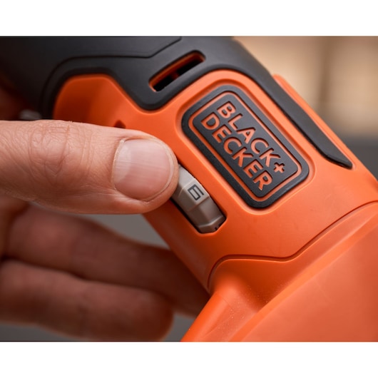 Close-up photo of a hand adjusting the speed dial on a BLACK+DECKER BDCOS18N orange power tool.