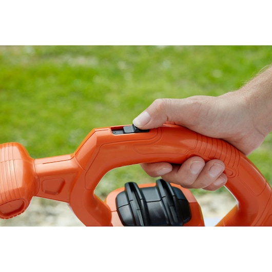 Photo of a hand pressing the trigger on the orange BLACKDECKER BEBLV260 leaf blower handle.