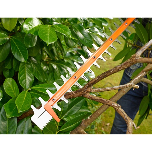 BLACKDECKER BEHTS401 hedge trimmer cutting thick tree branch outdoors, close-up on blades.