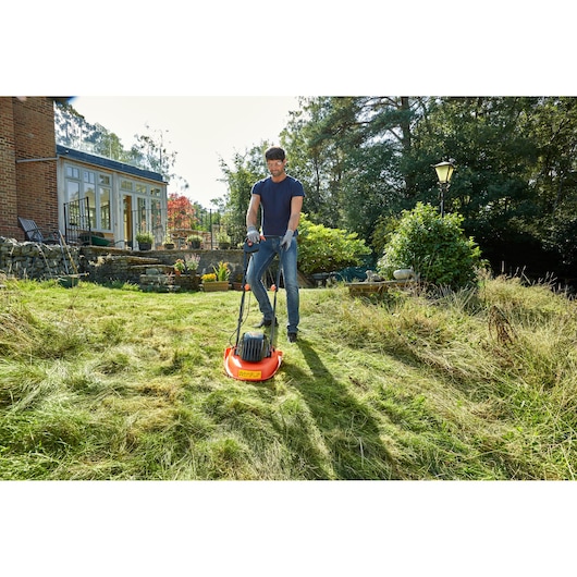 BLACKDECKER BEMWH551 lawn mower in use on grassy yard, person operating it outdoors near house.