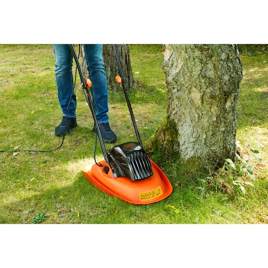 BLACKDECKER BEMWH551 hover lawn mower in use trimming grass near a tree outdoors.