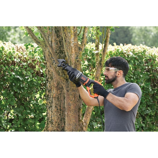 BLACKDECKER BES301K reciprocating saw being used for tree trimming outdoors, product category photography.