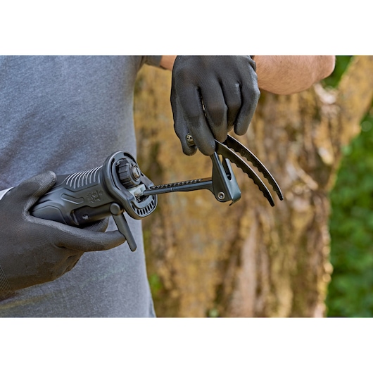 Photo of BLACKDECKER BES301K reciprocating saw held by gloved hands outdoors, close-up on front attachment.