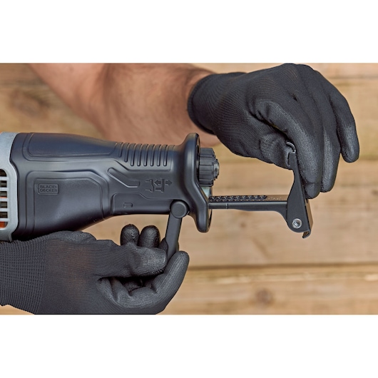 Photo of BLACK+DECKER BES301 reciprocating saw, close-up of gloved hands adjusting blade clamp.