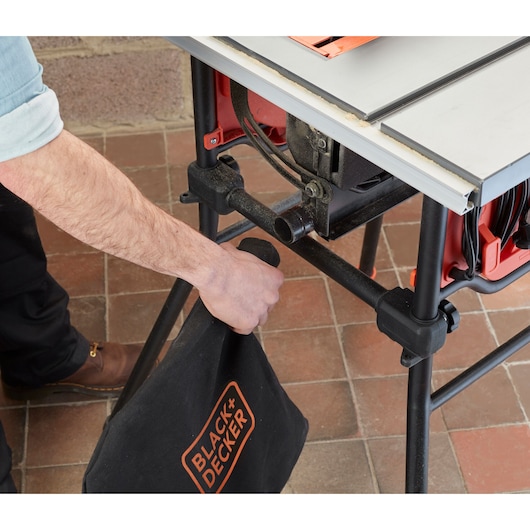 BLACK+DECKER BES720 table saw with dust bag attachment being installed, close-up side angle.