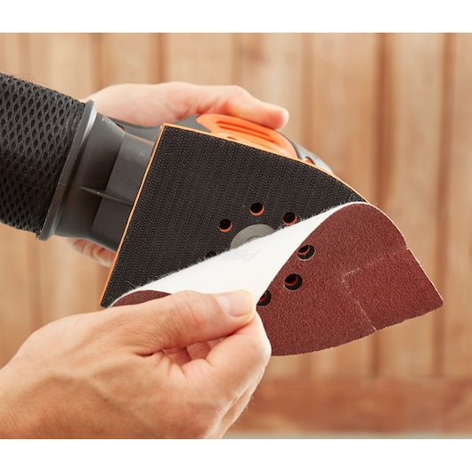 Photo of BLACKDECKER BEW200K detail sander with sanding sheet being attached, close-up view.