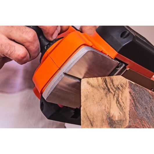 Close-up photo of BLACKDECKER BEW712 belt sander smoothing wooden plank, tool held by hand.