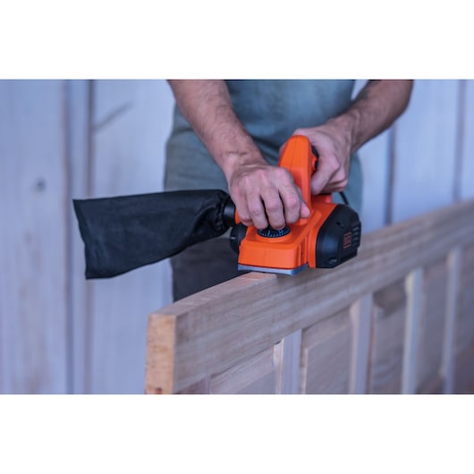 Photo of BLACKDECKER BEW712 electric planer in use on a wooden door edge, close-up view.