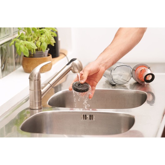 BLACKDECKER BHFEA515J vacuum filter rinsed under kitchen faucet, dust container on counter, photography.