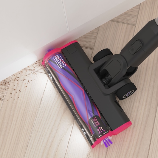 Photo of BLACK+DECKER BHFEA640WG cordless vacuum cleaner head with purple and pink details cleaning edge of light wood floor.