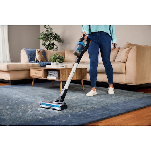 BLACKDECKER BHFEB520D1 cordless stick vacuum in use cleaning pet hair on blue carpet in living room.