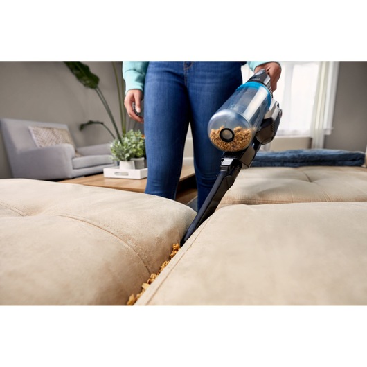 BLACKDECKER BHFEB520D1 handheld vacuum cleaning crumbs from beige couch crevice in living room, front angle.