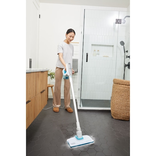 BLACKDECKER BHSM15FX08 steam mop cleaning black hexagon bathroom floor near glass shower.