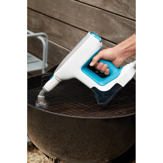 BLACKDECKER BHSM15FX08 handheld steam cleaner with blue accents cleaning a grill grate outdoors.