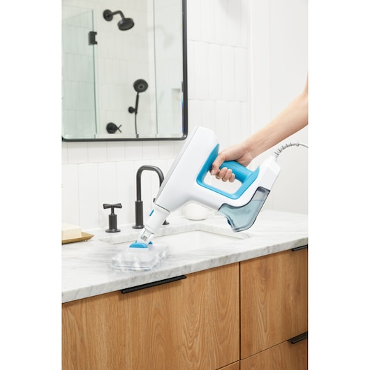 BLACKDECKER BHSM15FX08 handheld steam cleaner with blue accents cleaning bathroom countertop.