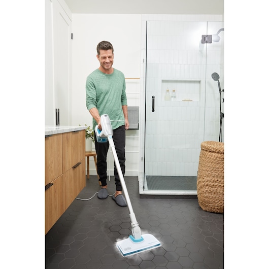 BLACKDECKER BHSM15FX08 steam mop cleaning black tile bathroom floor, handheld blue and white design.