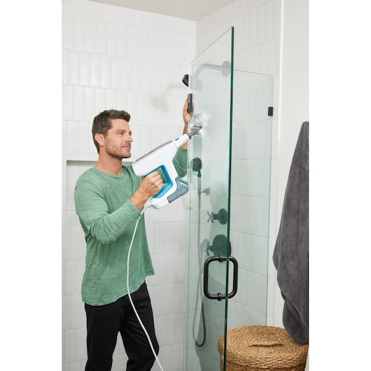BLACKDECKER BHSM15FX08 steam cleaning device used on glass shower door in bathroom setting.