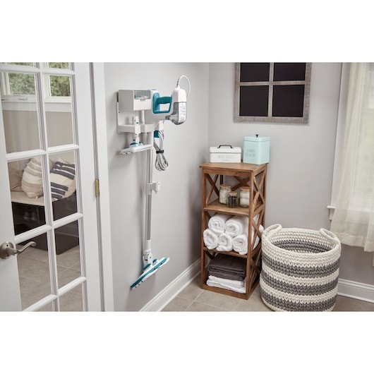 Photo of BLACKDECKER BHSM15FX10 steam mop mounted on wall in laundry room with storage basket and shelf.