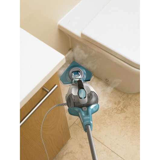 BLACKDECKER BHSM1610DSM steam mop cleaning bathroom floor corner near toilet and cabinet, releasing visible steam.