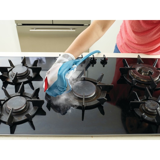 BLACKDECKER BHSM168DSM steam cleaning glove being used to clean a black gas stove top.