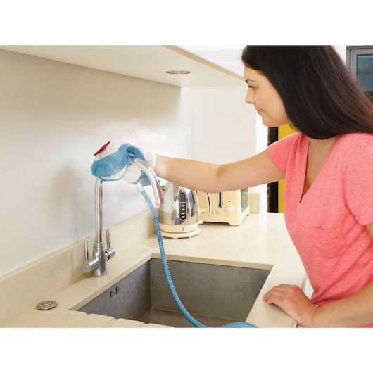 Photo of BLACKDECKER BHSM168DSM steam cleaner used on a kitchen faucet, person cleaning countertop area.