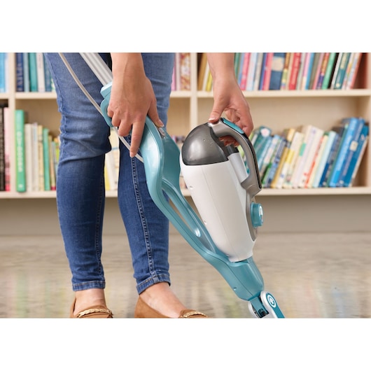 BLACKDECKER BHSM168DSM steam mop with detachable handheld unit, blue and white, in use on floor near bookshelf.
