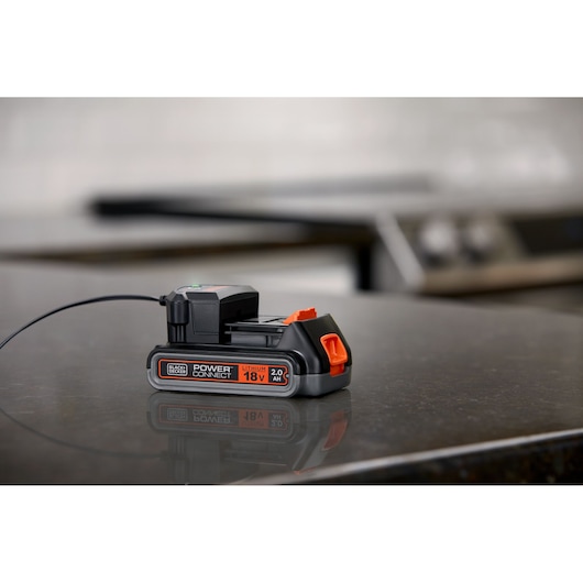 BLACKDECKER 18V 2.0Ah lithium battery BL2018 charging on a black countertop.