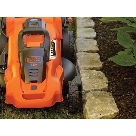 BLACKDECKER CLMA4820L2 lawn mower close-up near garden edging, orange and black finish.