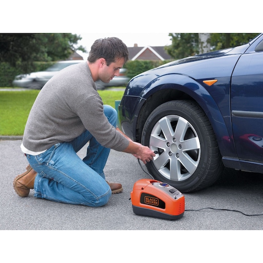 A man inflates a car tyre using the BLACK+DECKER 160 PSI AC/DC Multi Purpose Air Station.