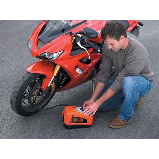 A man inflates a motorbike tyre using the BLACK+DECKER 160 PSI AC/DC Multi Purpose Air Station