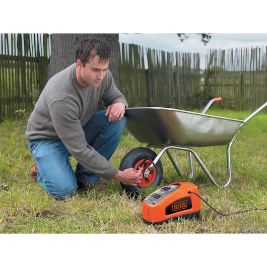 A man inflates a wheelbarrow tyre using the BLACK+DECKER 160 PSI AC/DC Multi Purpose Air Station