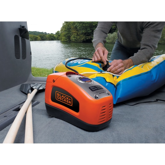 A man inflates a rubber dinghy using the BLACK+DECKER 160 PSI AC/DC Multi Purpose Air Station