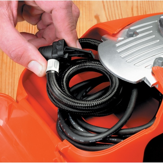 Close-up of a hand holding the air hose valve included with the BLACK+DECKER 160 PSI AC/DC Multi Purpose Air Station.