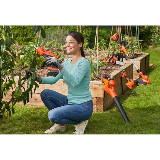 Using BLACK+DECKER 18V Power Pruner outdoors, with other 18V POWERCONNECT tools in background