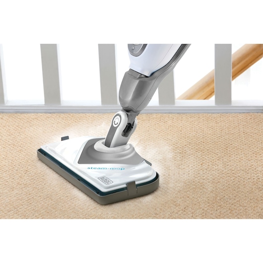 BLACKDECKER FSMCG steam mop cleaning beige carpet, close-up angle.