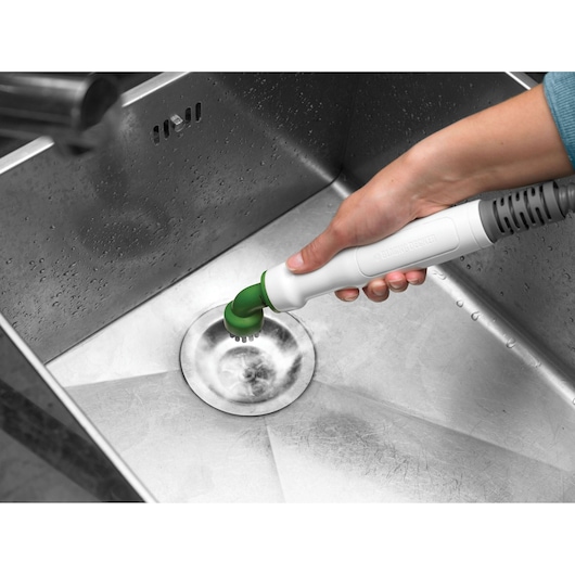 BLACK+DECKER FSMH1321 steam cleaner with green brush attachment cleaning a stainless steel sink, angled view.